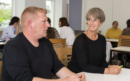 En kvindelige og en mandlig studerende på meritpædagoguddannelsen snakker sammen og skriver på et stykke papir