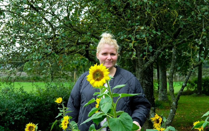Stine Marthine Pedersen står blandt solsikker i haven i Brørup.