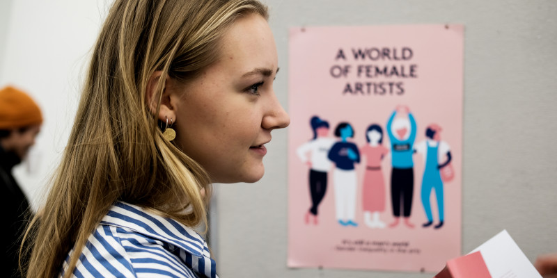 Studerende på grafisk kommunikation står foran plakat